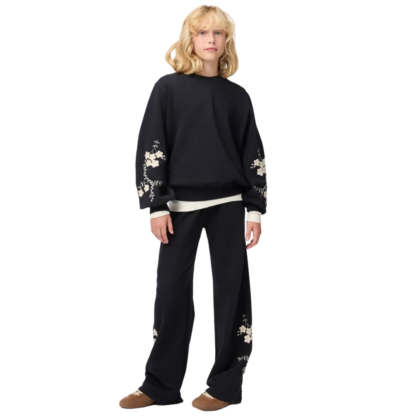 Person wearing a black sweater with floral embroidery on a white background