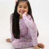 Young girl wearing a pink rainbow-themed outfit on a white background