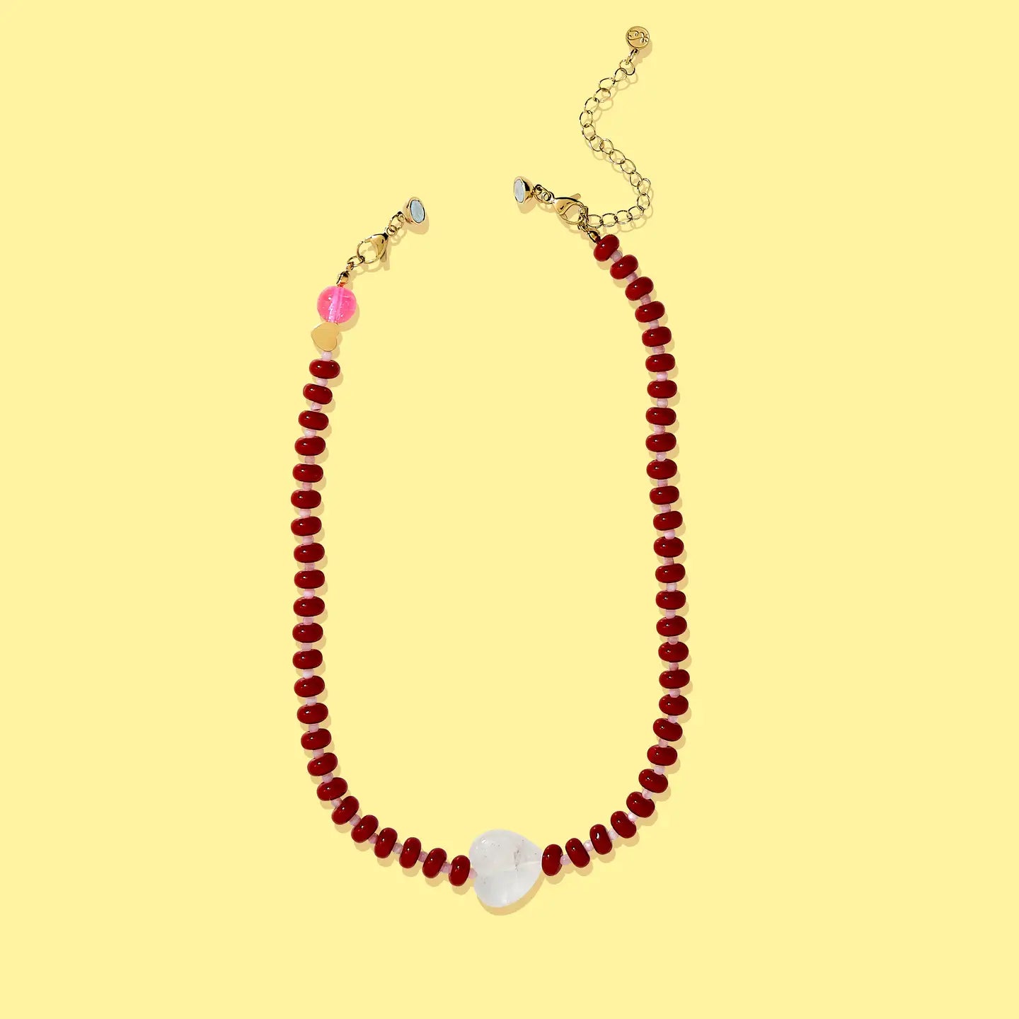 Necklace with red beads and a white pendant on a yellow background