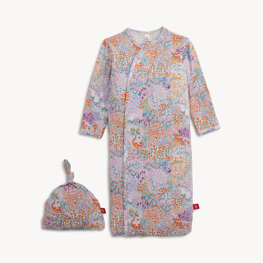 A baby hat and gown set with a colorful floral and abstract print on a light pink background.