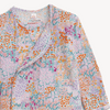A close up of a baby gown with a colorful floral and abstract print on a light pink background.