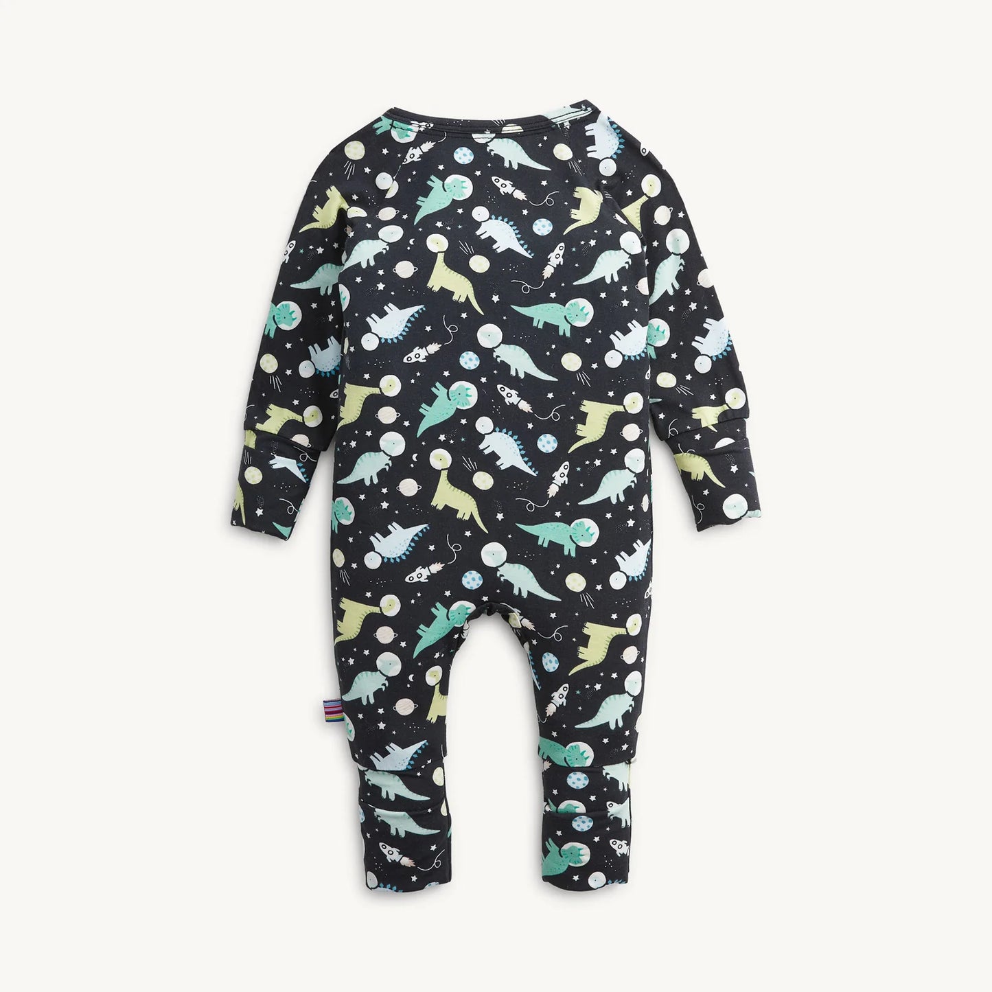 A baby long-sleeve one-piece coverall with an all-over dinosaur space print on a black background, shown against a light off-white background.