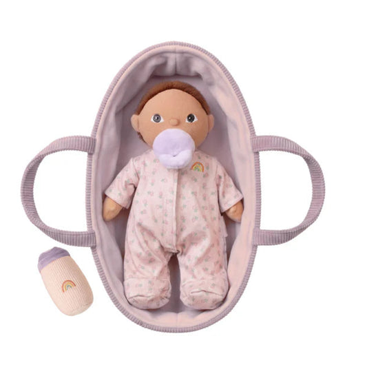 Baby doll in a pink crib on a white background