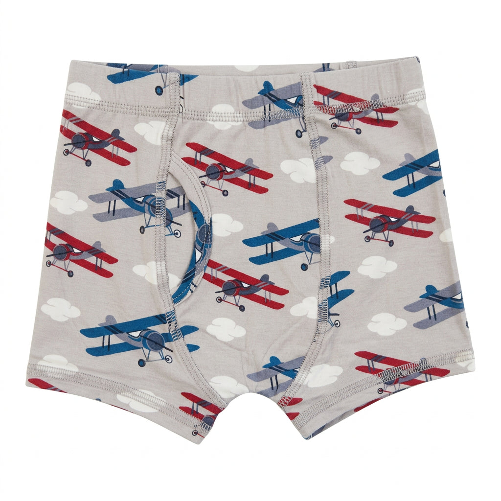 A pair of toddler boy's boxer briefs featuring an all-over print of red, blue, and gray vintage biplanes on a light gray background, with white clouds. 