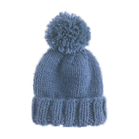 A dusty blue chunky knit beanie hat with a matching pom-pom on top, shown against a plain white background.