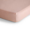 Close-up of a fitted sheet on a bed with a light pink color.