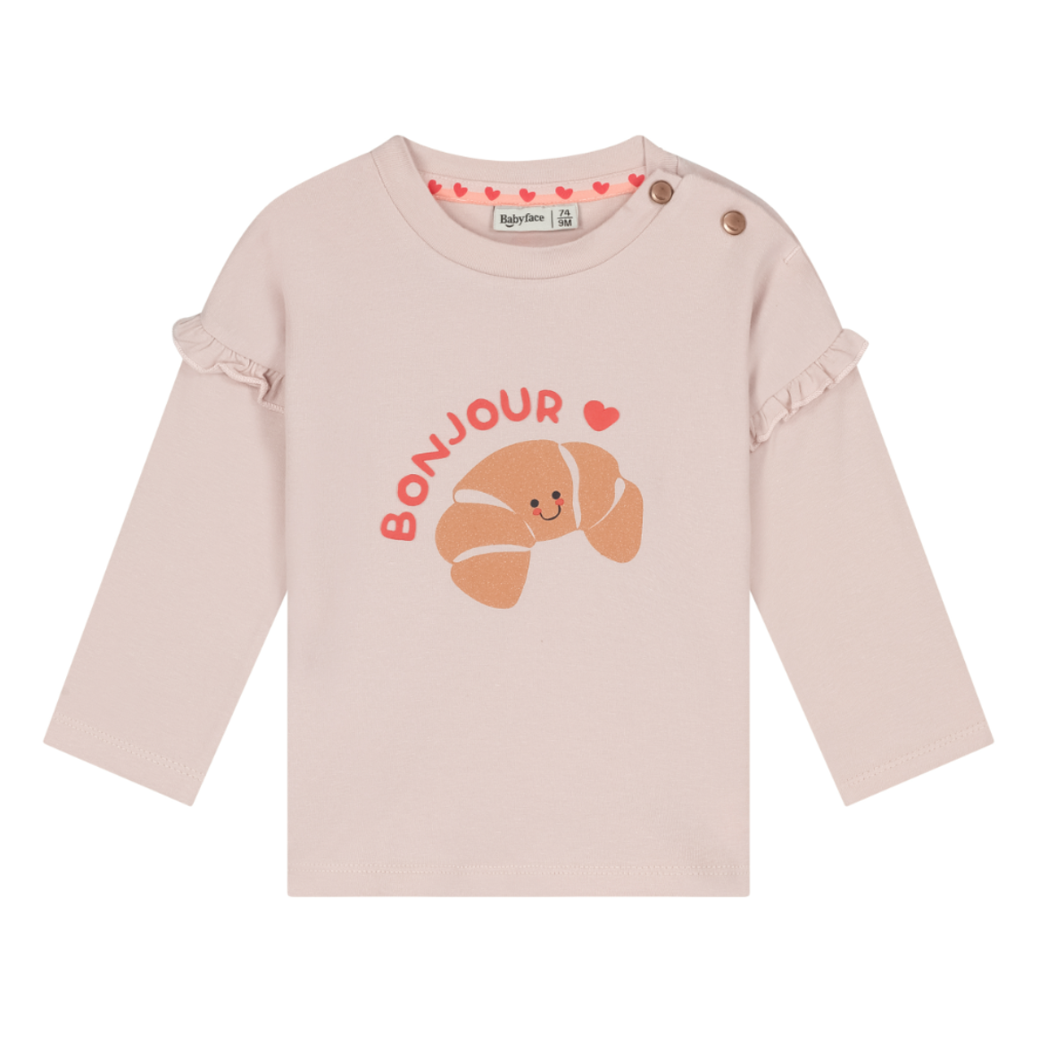 A light pink long-sleeve baby top with a croissant graphic and 'BONJOUR' text on the front, featuring ruffled cuffs and snap closures at the shoulder.