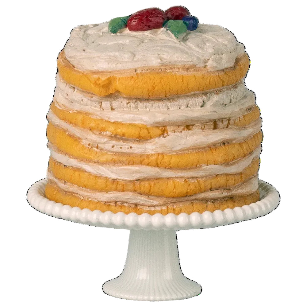 Layered cake with white frosting and fruit on top, placed on a white cake stand.