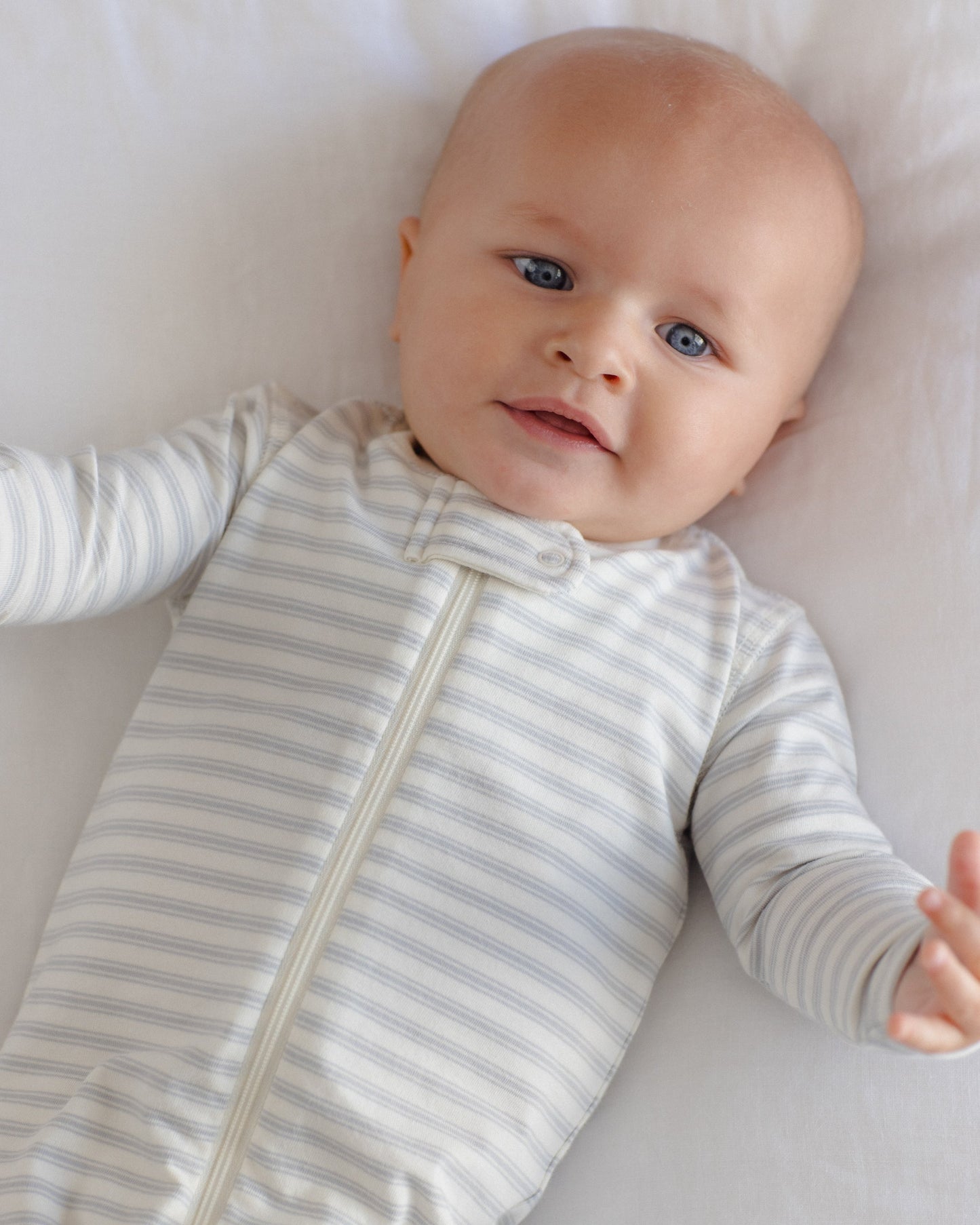 Baby wearing the Cloud Stripe Zip Footie by Quincy Mae, lifestyle photo