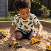 Child wearing a beige tshirt with blue and yellow tractor pattern, playing in sandbox