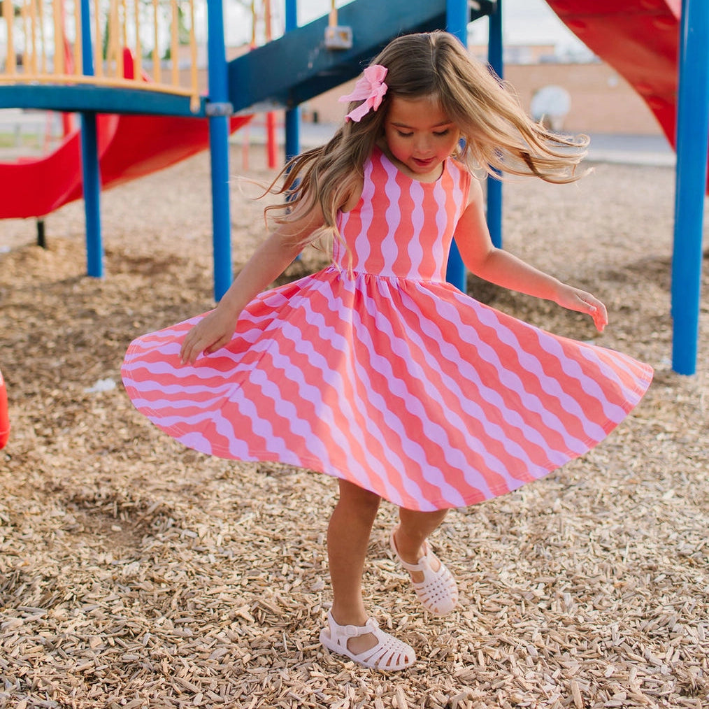 Child in a pink and white checkered dress at a playground