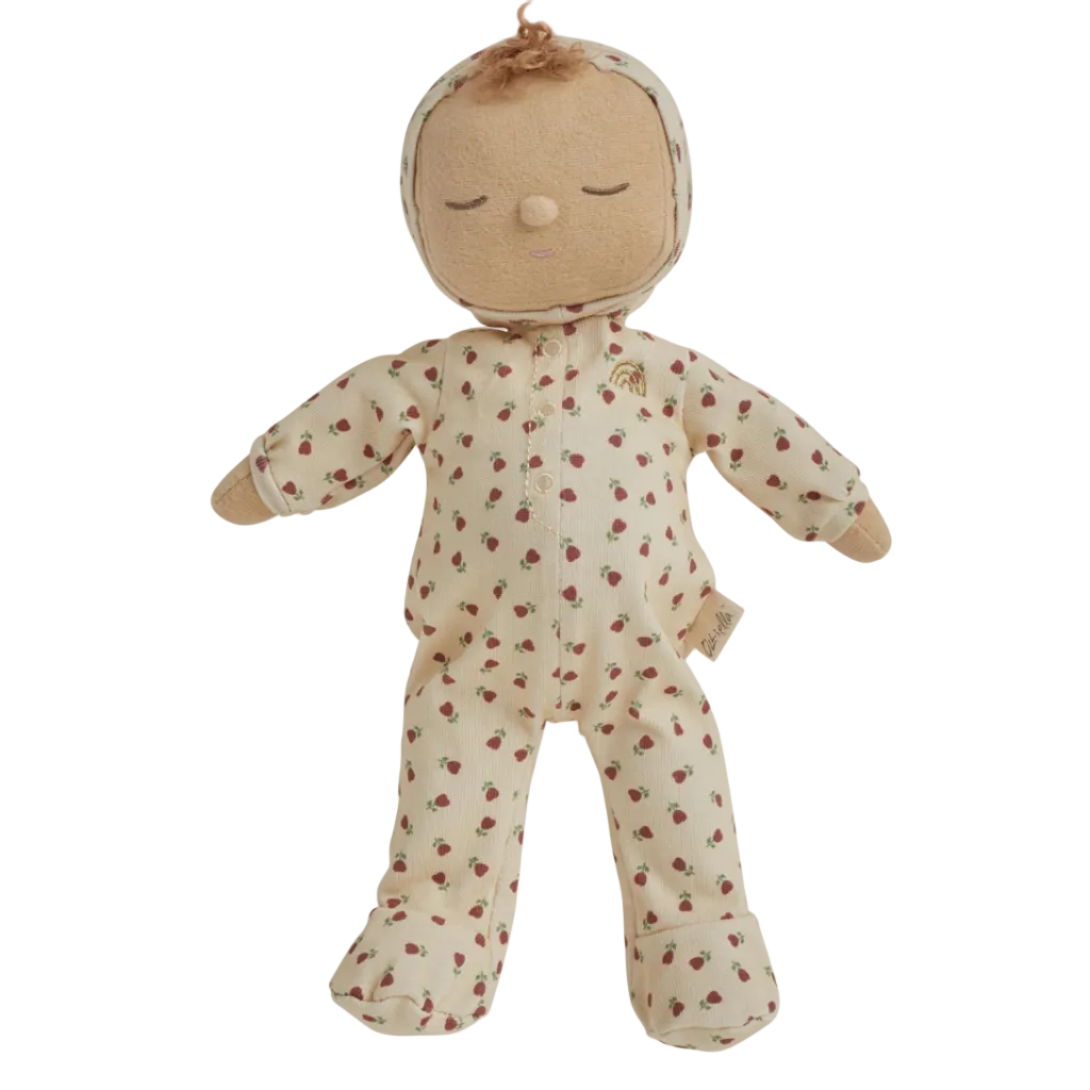 A plush baby doll wearing a cream-colored footed onesie with a small red strawberry pattern, set against a plain white background.