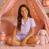 Young girl sitting inside a pink play tent wearing pastel plaid short sleeve lounge set