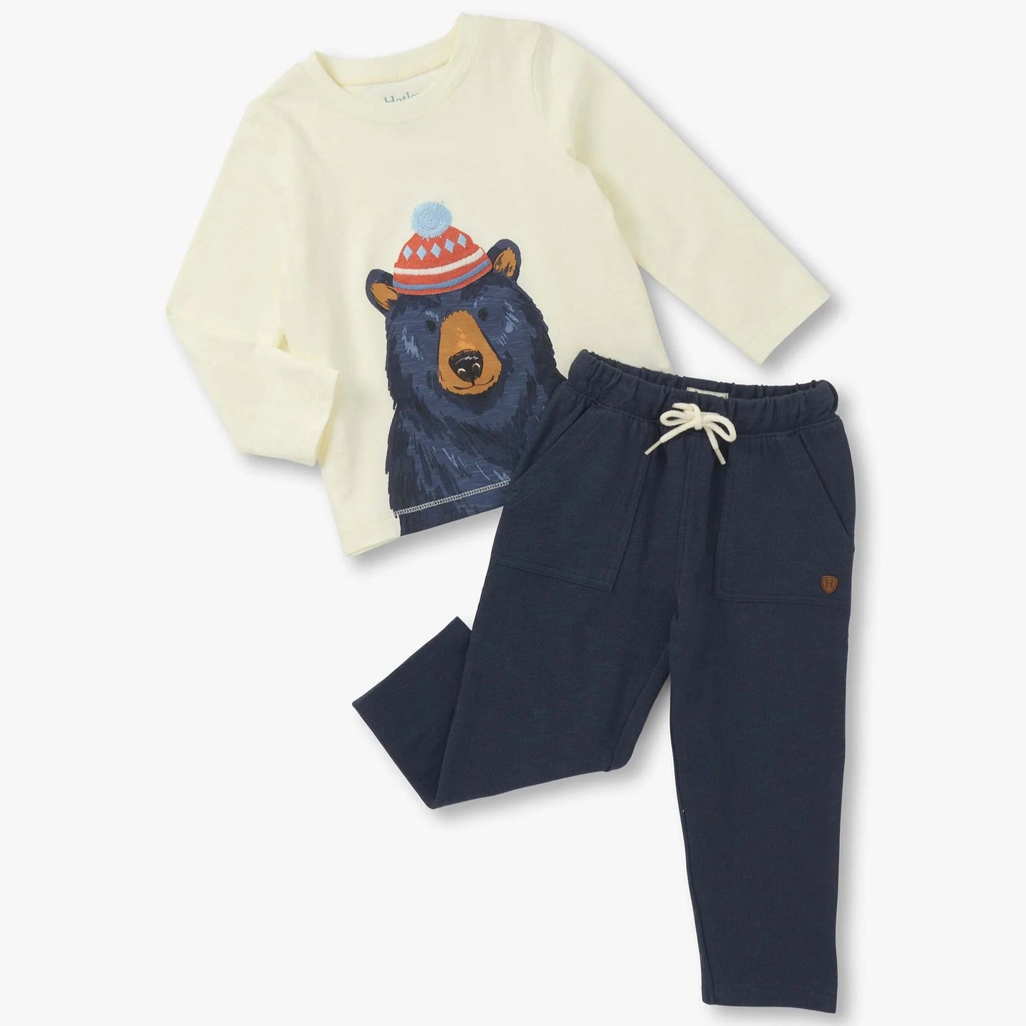 Children's outfit with a cream sweater featuring a bear design and navy pants on a white background