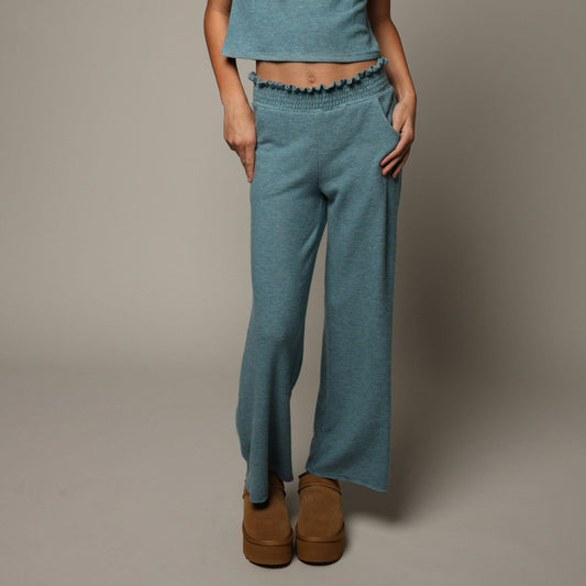 Woman wearing a teal smocked waistband straight pant. 