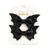 Two black sequined bat-wing shaped hair bows attached to a white Sweet Wink card, photographed on a white background.