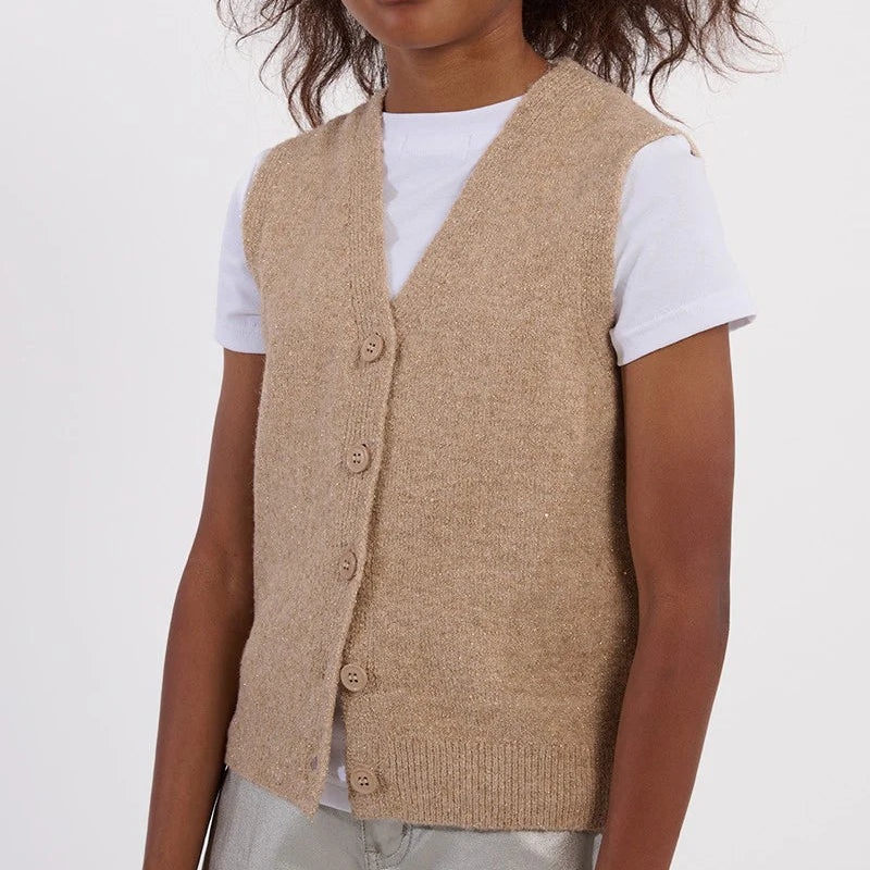 Child wearing a beige vest over a white shirt on a plain background