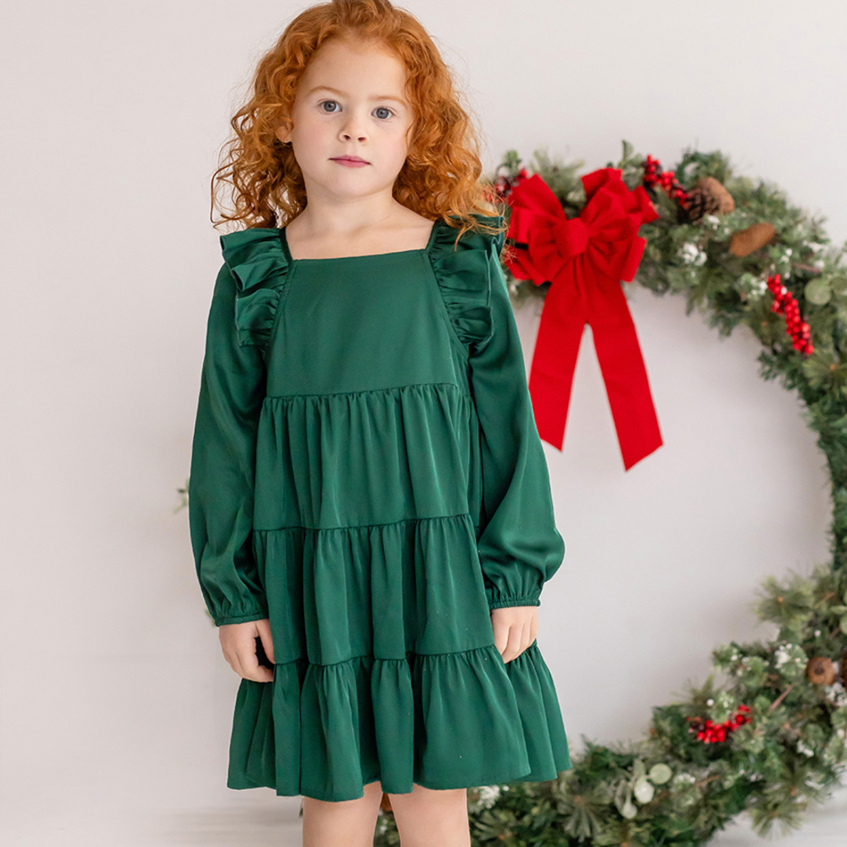 Girl standing in a green long sleeved ruffle dress