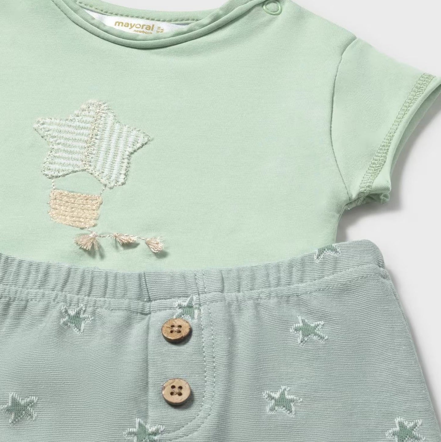 Light green baby outfit with star patterns on a white background