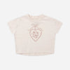 A light beige short-sleeve crop top with a rose gold glittery heart graphic on the chest.
