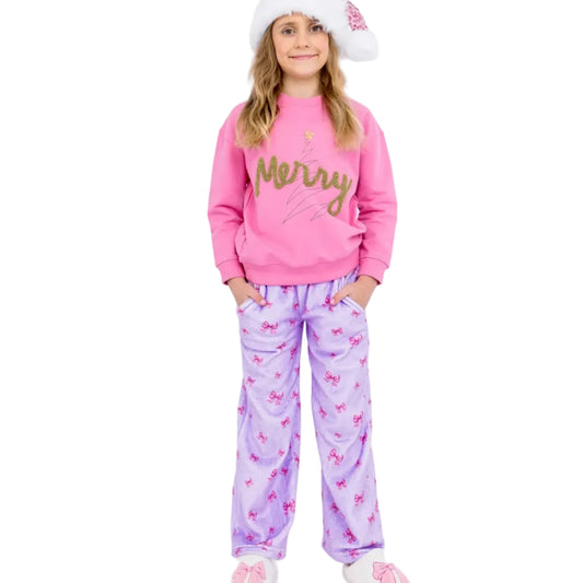 Person wearing a pink 'Merry' sweatshirt and purple pajama pants with a bow pattern