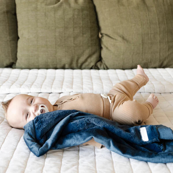 Baby lying on a bed with a blue blanket