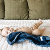 Baby lying on a bed with a blue blanket