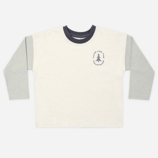 A long-sleeve ringer t-shirt in off-white with light gray sleeves and a dark navy collar, featuring a small circular chest graphic with a tree and the text 'The Pine Tree Company'.