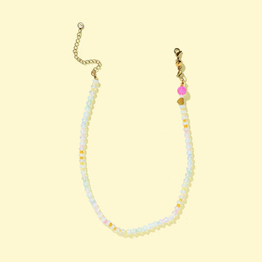 Beaded necklace with gold chain on a light yellow background