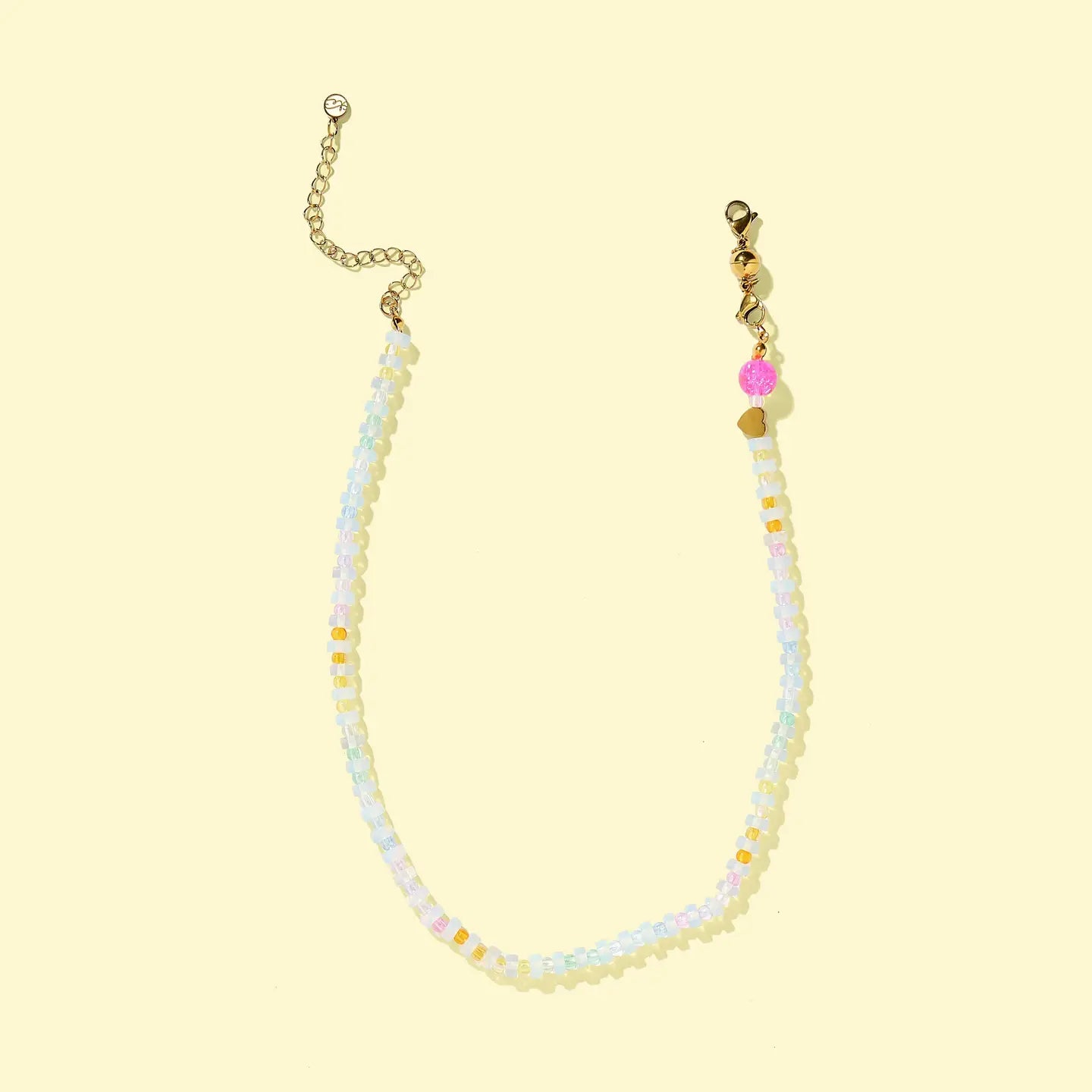 Beaded necklace with gold chain on a light yellow background