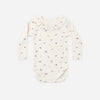 An off-white long-sleeve baby bodysuit with a delicate, small all-over floral print, featuring a ruffled collar and ribbed texture, laid flat against a light gray background.