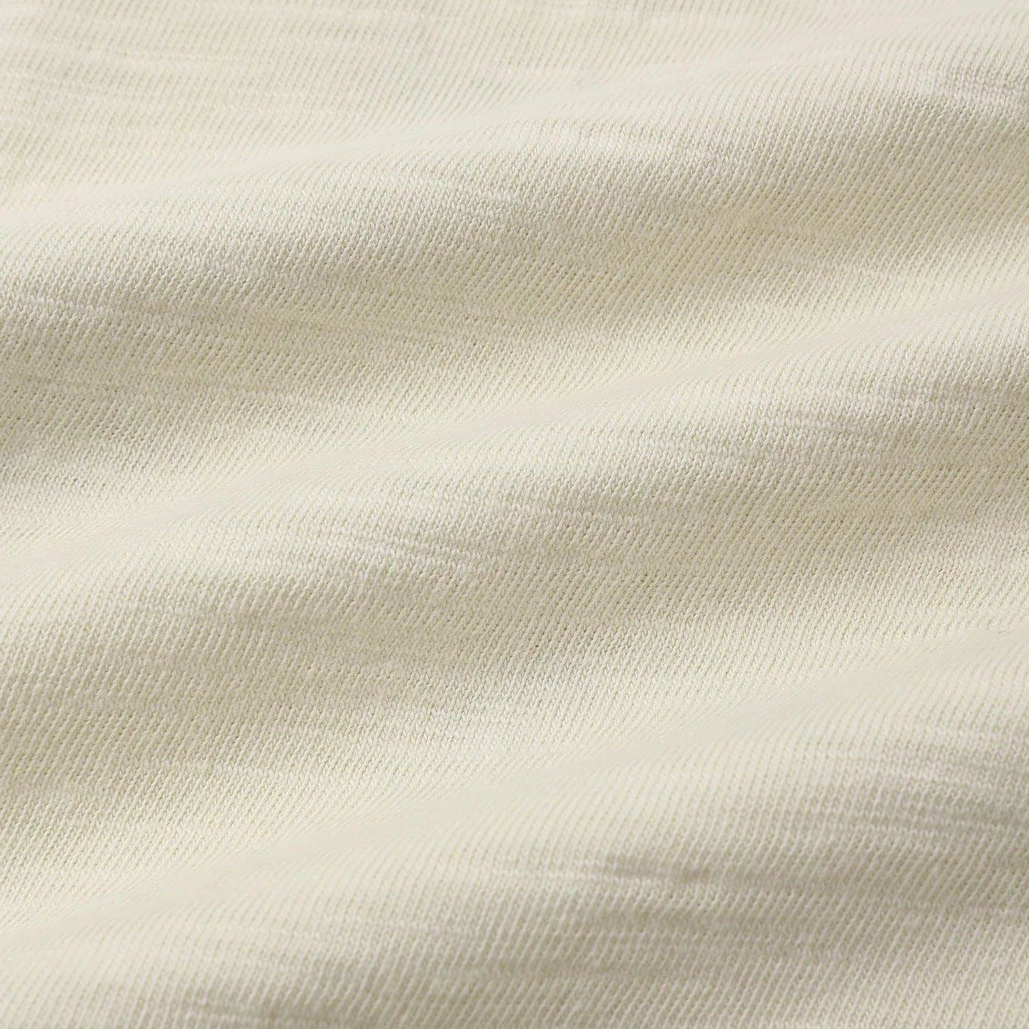 A close-up of a light cream or off-white textured fabric with soft folds and a linen-like weave.