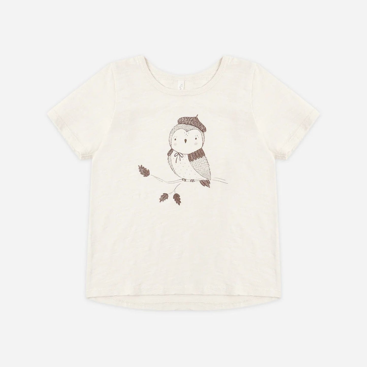 An off-white short-sleeve t-shirt featuring a cute cartoon owl wearing a brown knit hat and scarf, sitting on a branch with two small leaves.