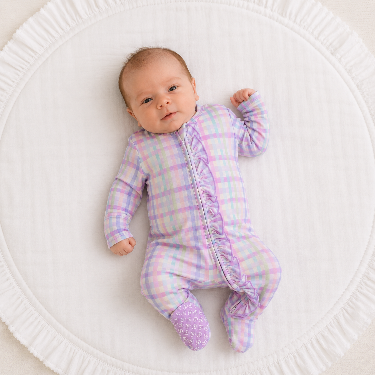 Baby wearing a purple and pink checkered zip footle pajama with ruffles