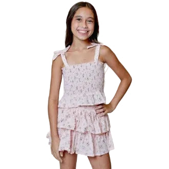 Young girl wearing a pink floral skirt with a decorative background of flowers.