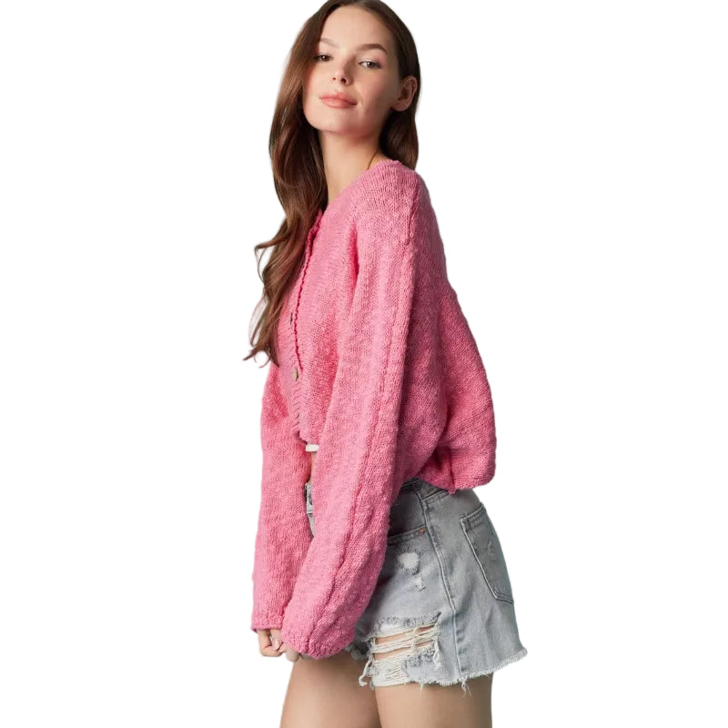 Woman wearing a pink sweater and denim shorts against a light blue background