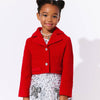 Young girl wearing a red jacket and white dress with black patterns on a white background
