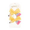 Two yellow bow hair clips on a Sweet Wink branded card.