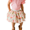 Girl wearing a pink top and patterned skirt on a plain background