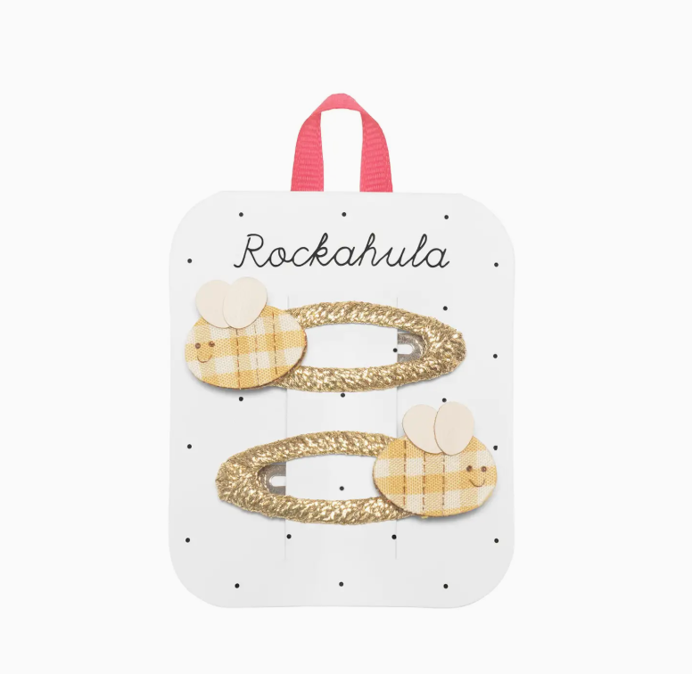 Two gold-colored hair clips with bee designs on a white display card, branded Rockahula.