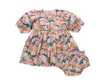 Floral baby romper with puff sleeves on a pink background