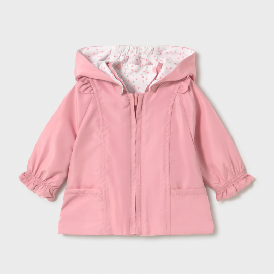 Pink reversible baby coat with dotted lining on a light gray background