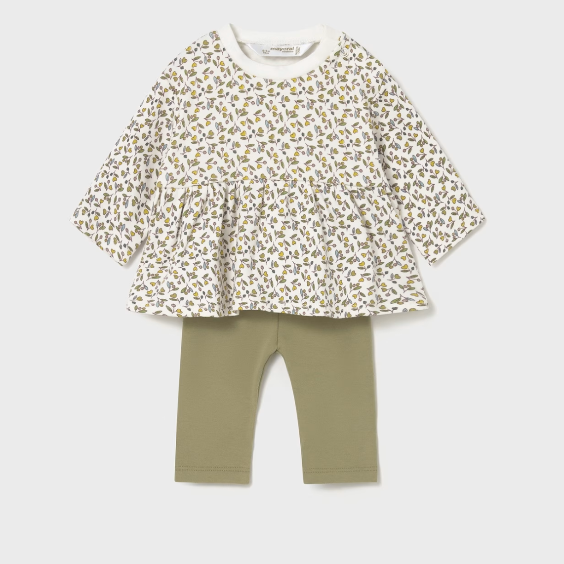 Children's outfit with floral top and green leggings on a light gray background