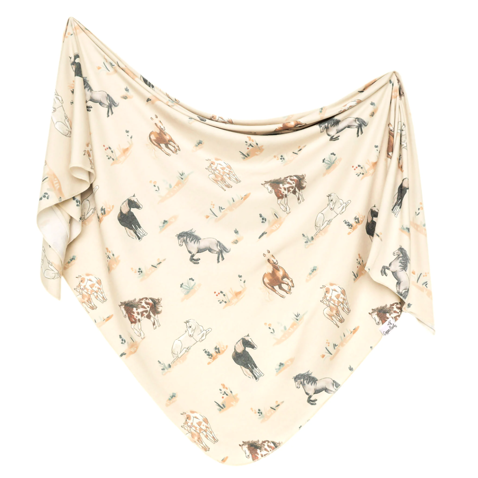 Beige baby blanket with horse pattern on a white background