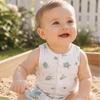 Baby playing in a sandbox with sand toys, where a white romper with green sea turtle print
