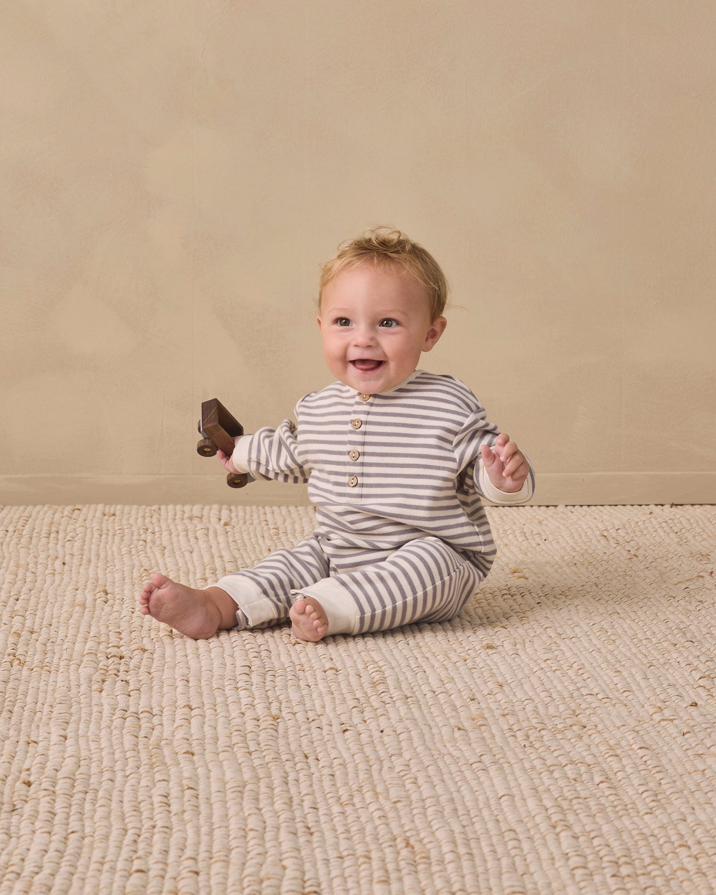 Baby wearing the Slate Stripe Henley Jumpsuit by Quincy Mae