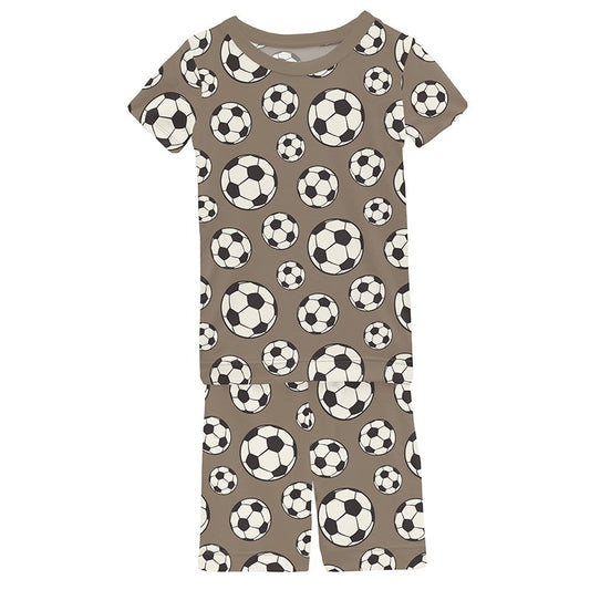 Boys short sleeve pajama set with soccer ball pattern on a brown background.