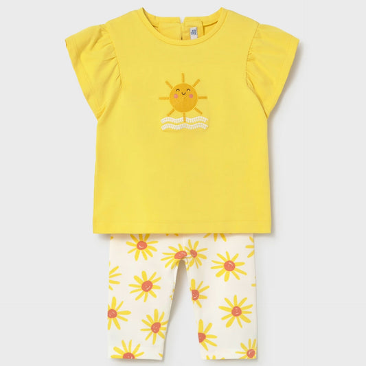 Yellow top with sun design and white pants with floral pattern on a light gray background