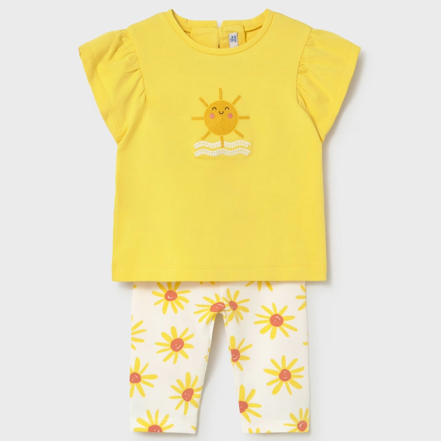 Yellow top with sun design and white pants with floral pattern on a light gray background