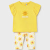 Yellow top with sun design and white pants with floral pattern on a light gray background